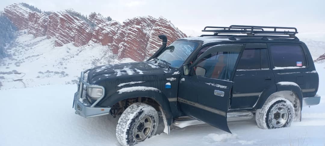 Off-road 4x4 Jeep driving through a mountain pass in Kyrgyzstan
